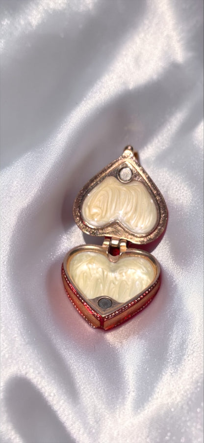 Gold-tone heart-shaped trinket box with rhinestone accent and pearly interior.