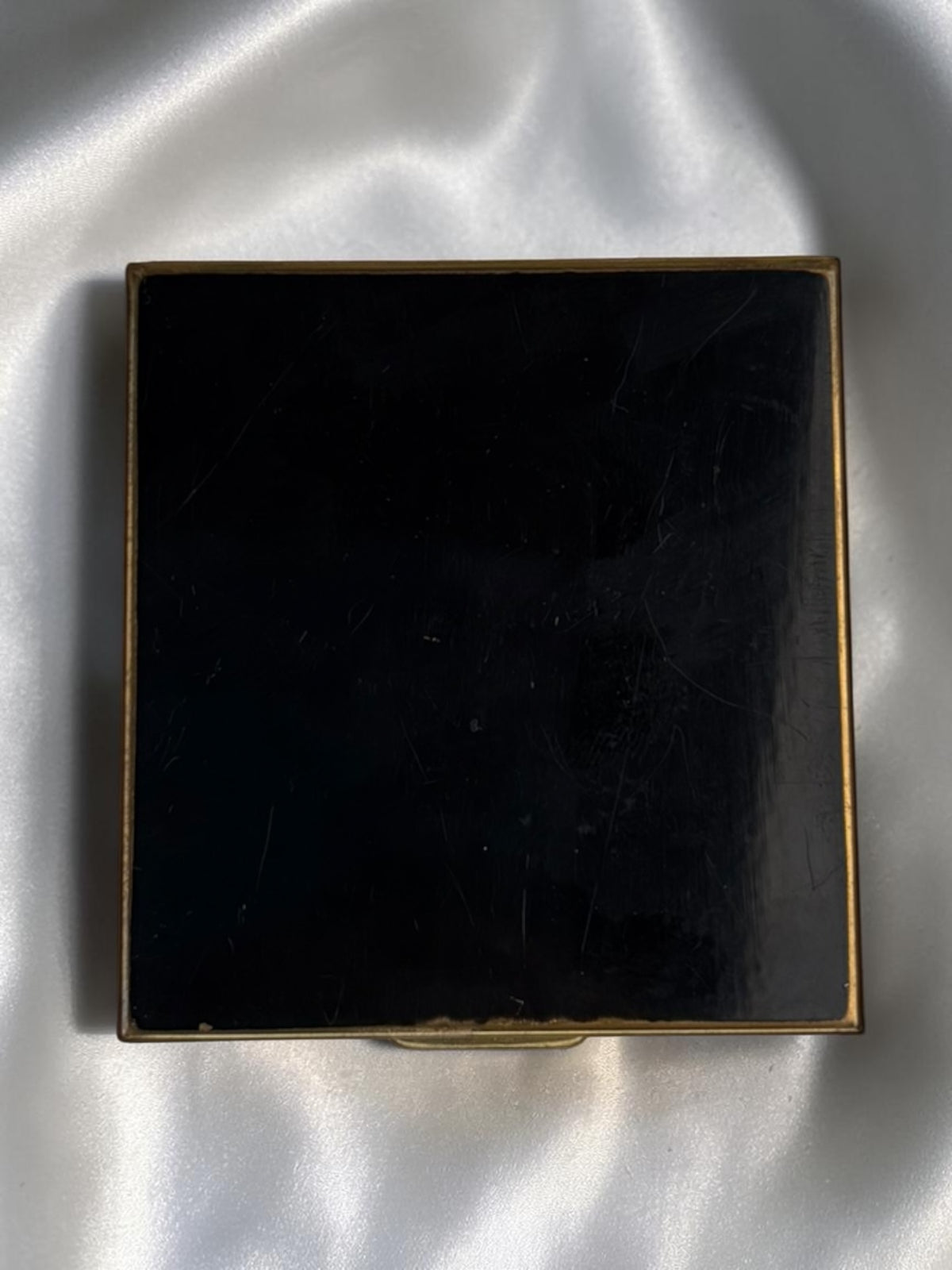 1940s black enamel compact with floral basket motif and gold trim.
