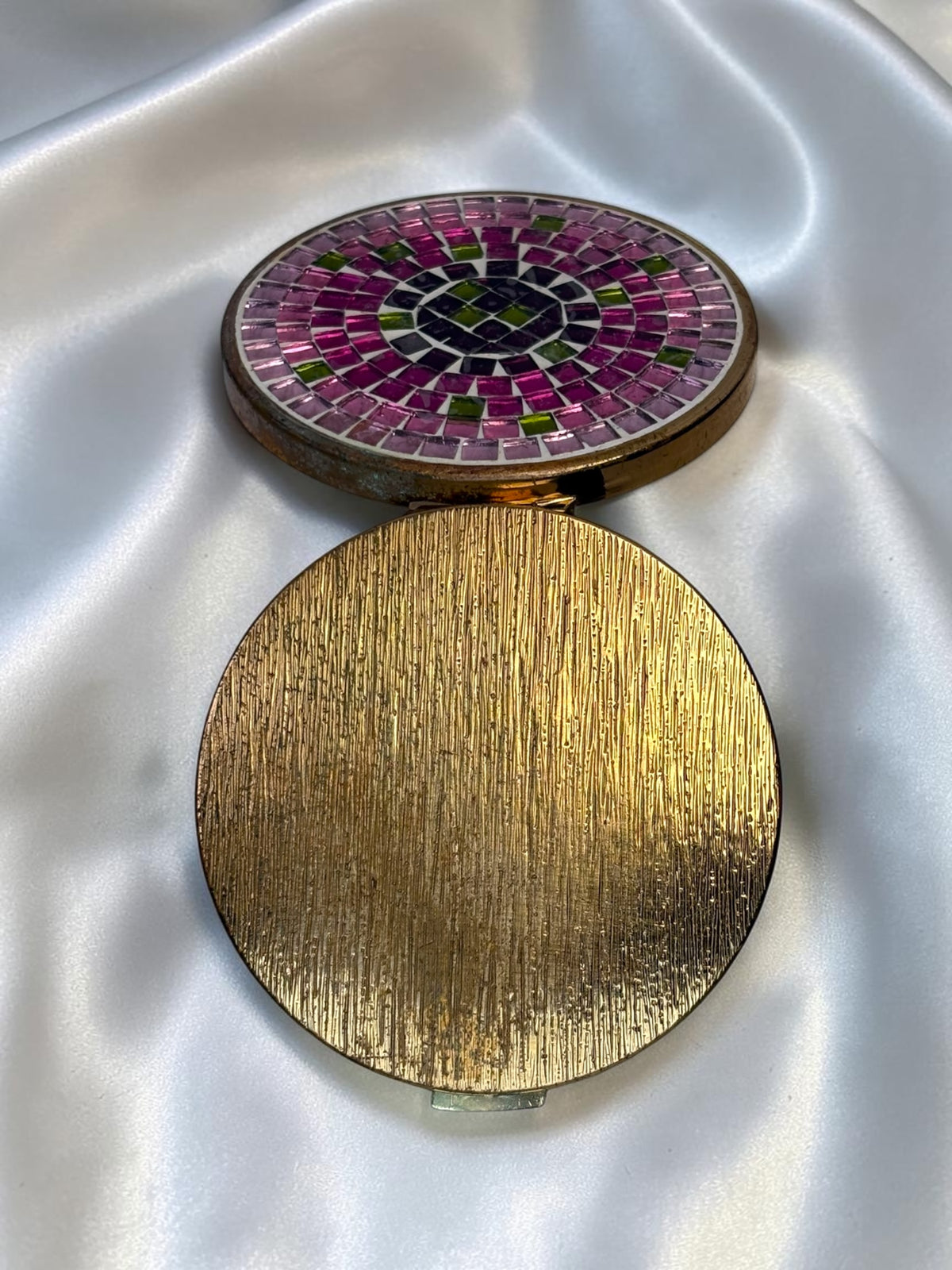 1940s vanity compact with pink and green mosaic glass lid and textured gold base.