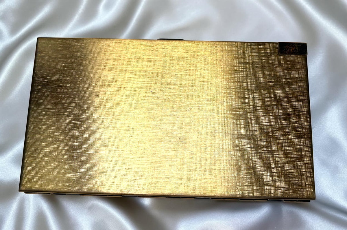 Gold textured compact purse with a dark accent in the top right corner.